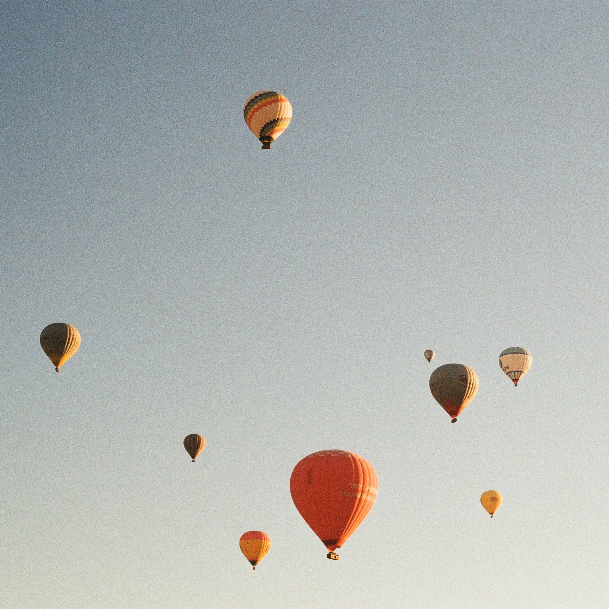 Multiple hot air balloons floating in a clear blue sky.