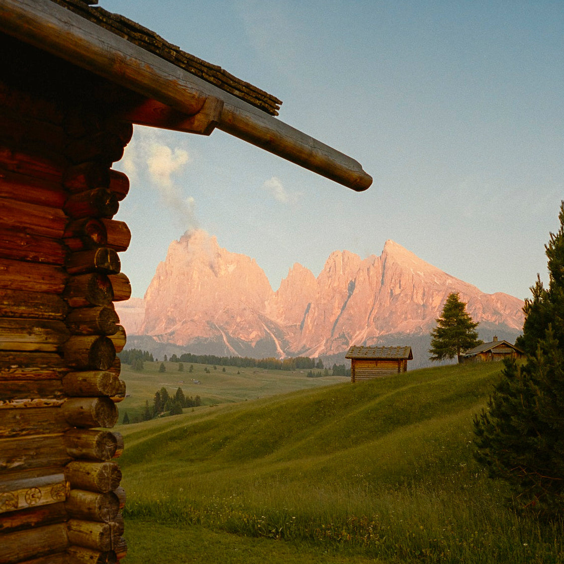 Log cabin with a scenic view of mountains and green fields